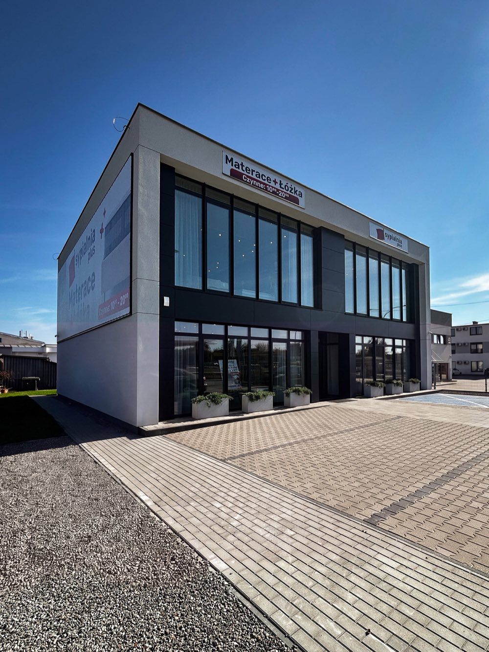Salon SypialniaPlus — budynek z parkingiem przed wejściem