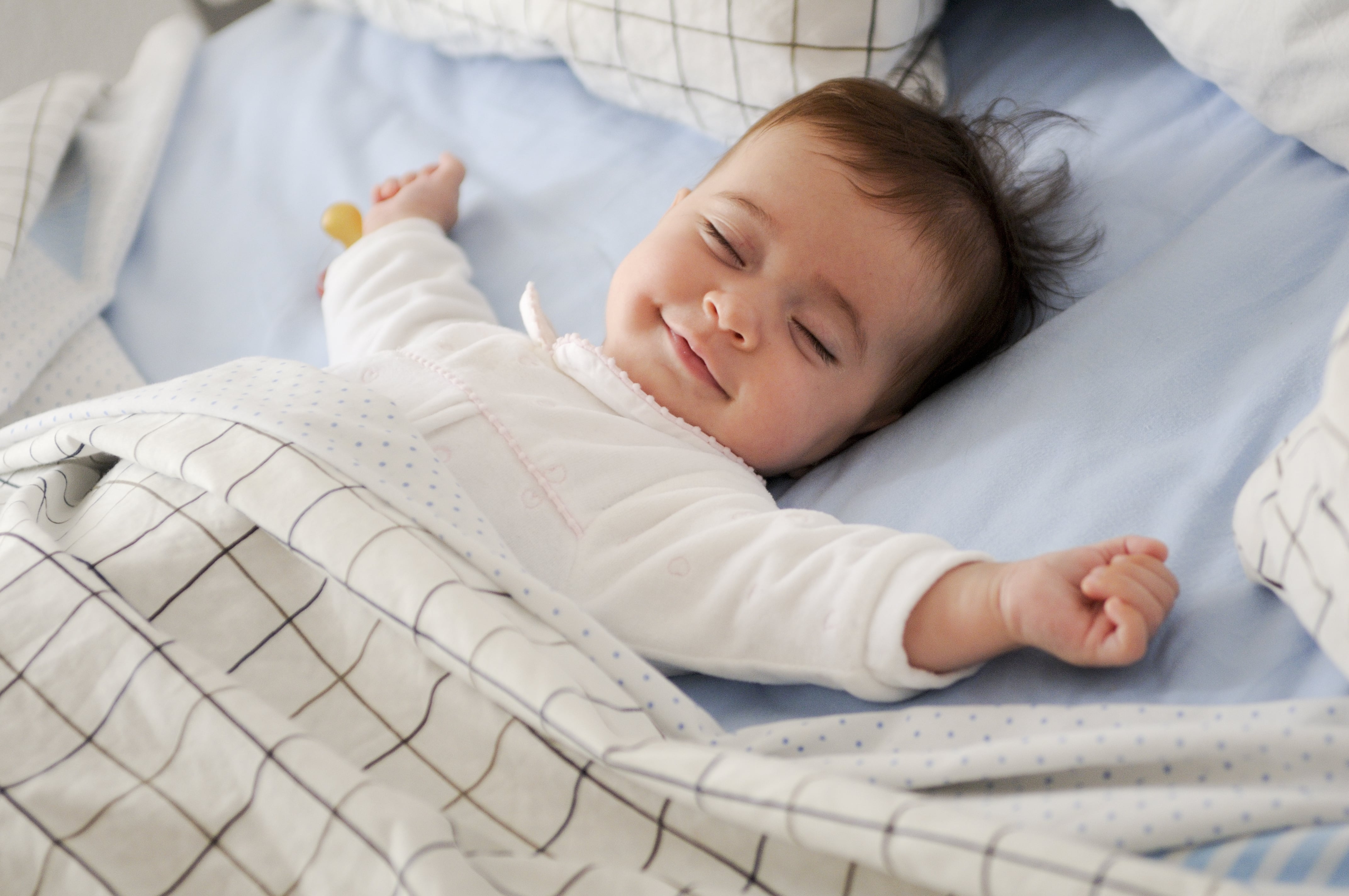 Uśmiechnięte dziecko śpi w łóżeczku